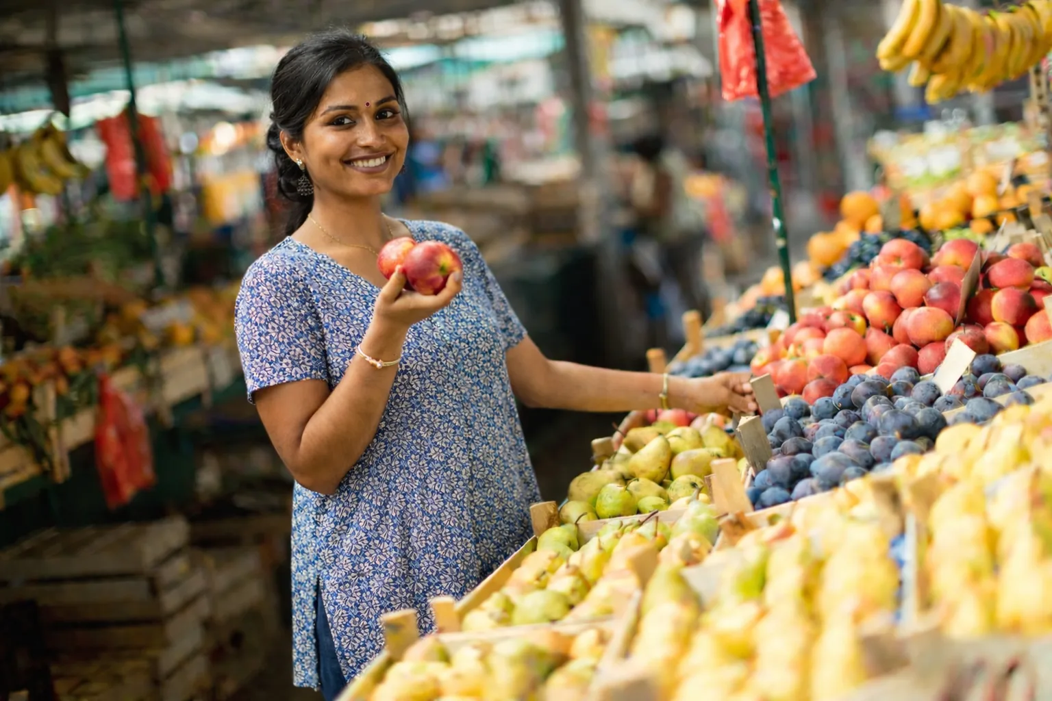 Fresh fruit vendor carefully sorting apples and oranges at a Bangalore market